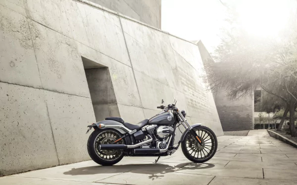 HD PC desktop wallpaper showing a Harley-Davidson Breakout motorcycle parked by a modern concrete wall in soft sunlight.