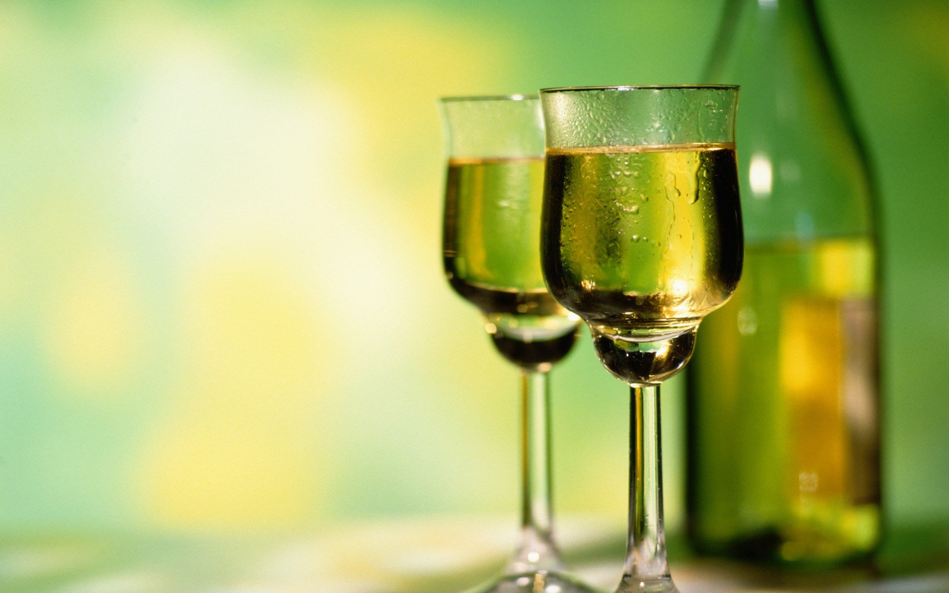 HD PC desktop wallpaper featuring two glasses of white wine with a blurred green and yellow background, highlighting food and drink themes.
