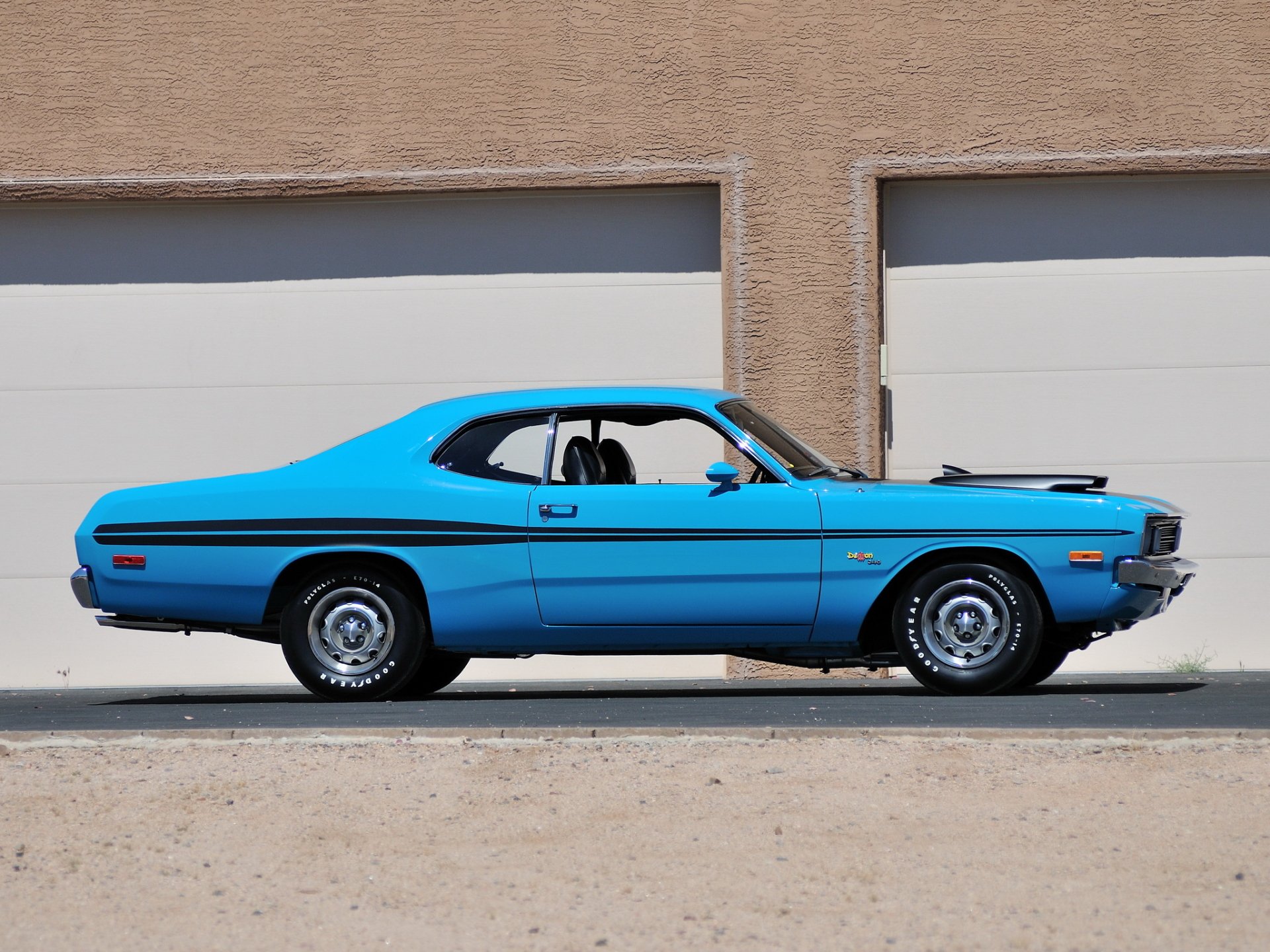 Blue Mopar Dodge Demon 340 muscle car vehicle parked sideways against garage doors — HD PC desktop wallpaper background.