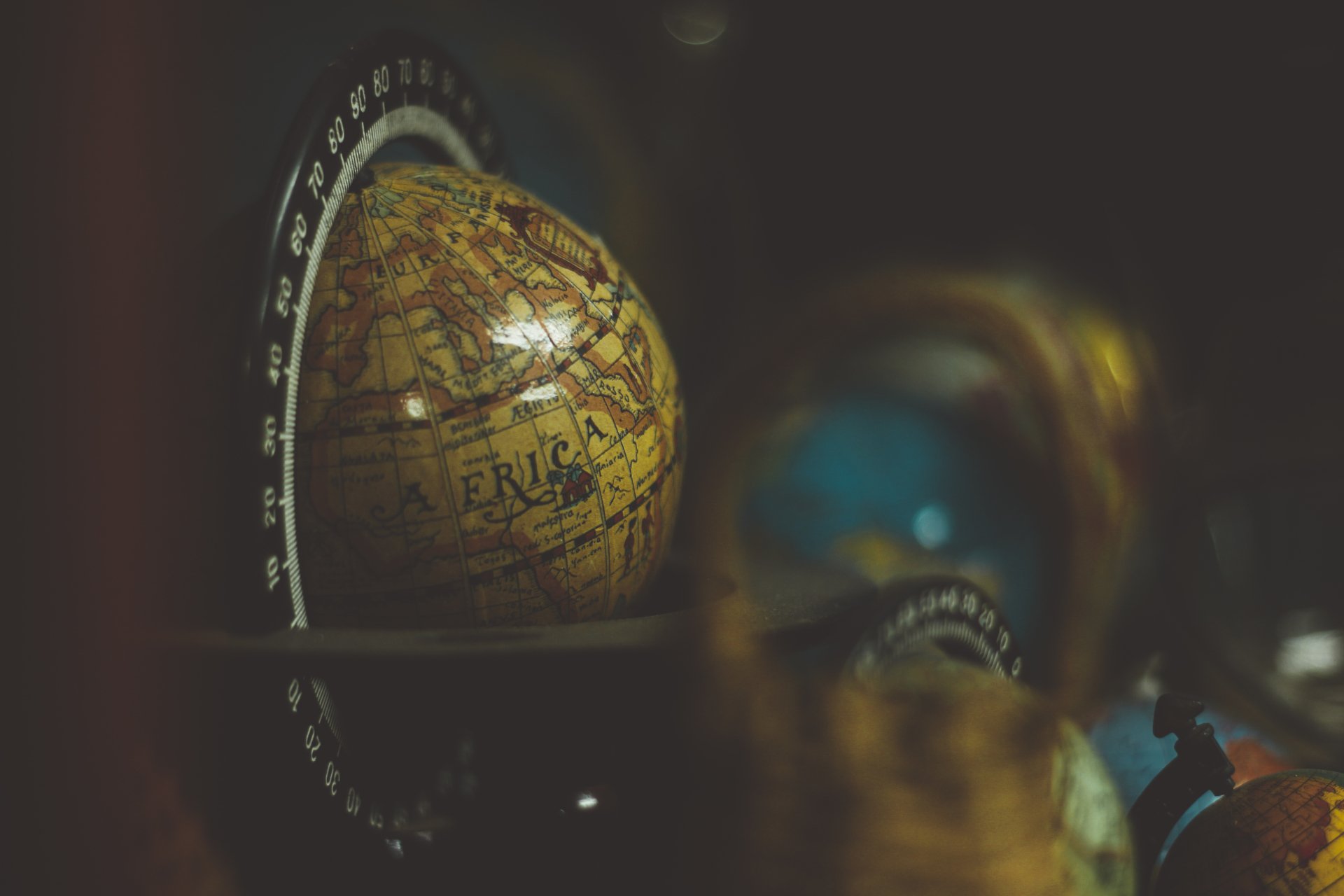 A 4K Ultra HD blurred image of a man-made globe, highlighting the continent of Africa with warm, muted tones on a dark background.