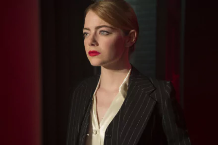 Emma Stone in a striking pose from the movie La La Land, featuring her in a stylish pinstripe outfit with bold red lips, set against a dramatic backdrop. HD desktop wallpaper.