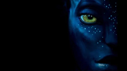 HD desktop wallpaper featuring a close-up of a blue-skinned character's face from the movie Avatar, with striking yellow eyes and glowing white spots against a dark background.