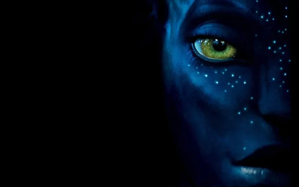 HD desktop wallpaper featuring a close-up of a blue-skinned character's face from the movie Avatar, with striking yellow eyes and glowing white spots against a dark background.