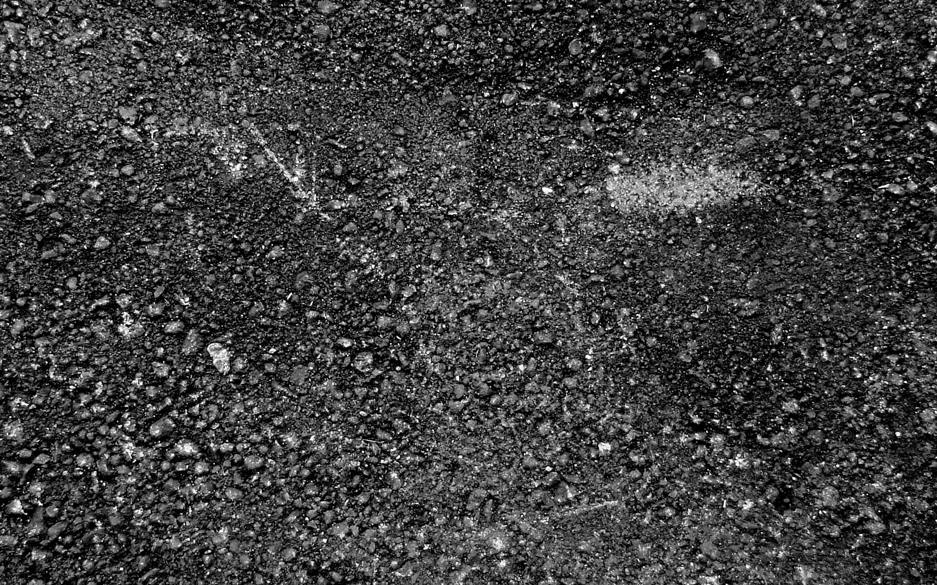 HD PC desktop wallpaper featuring a high-contrast abstract texture of rough, dark gravel with scattered lighter patches.