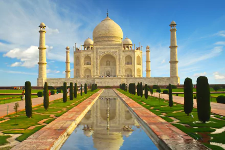 HD desktop wallpaper of the Taj Mahal in India, featuring its iconic dome and reflection in the central pool, surrounded by manicured gardens and blue sky.