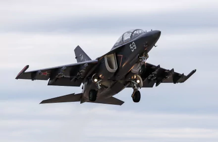 Military Yakovlev Yak-130 jet fighter warplane captured mid-flight against a cloudy sky in this HD desktop wallpaper and background.