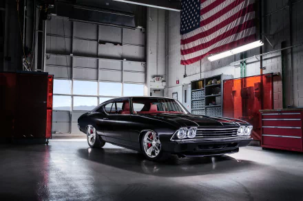 A sleek black Chevrolet Chevelle muscle car parked inside a garage with an American flag hanging overhead, captured in high-definition for a PC desktop wallpaper.