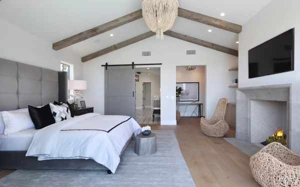 Modern bedroom with vaulted ceiling, wooden beams, a large bed, fireplace, and stylish furniture, captured in 4K Ultra HD for PC desktop wallpaper use.