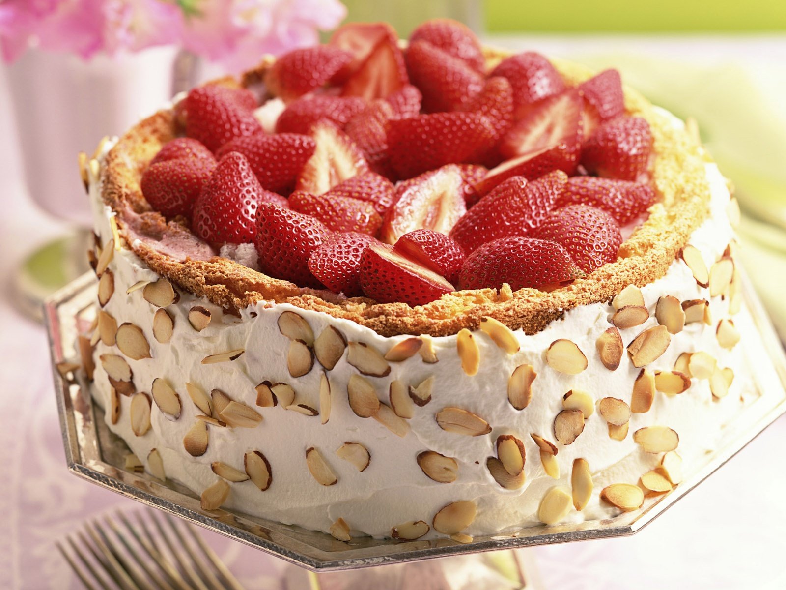HD desktop wallpaper of a delicious cheesecake adorned with fresh strawberries on top and almond slices on the side.