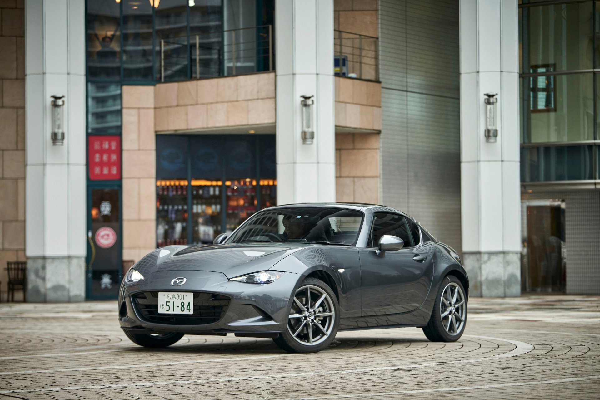 HD desktop wallpaper featuring a sleek silver Mazda MX-5 car parked in an urban setting, showcasing the vehicle's sporty design and modern style.