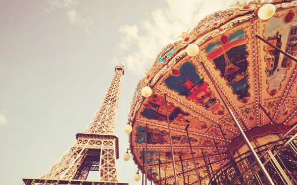 HD PC desktop wallpaper: Paris, France — colorful carrousel in the foreground with the man-made Eiffel Tower monument rising behind beneath a pale sky.