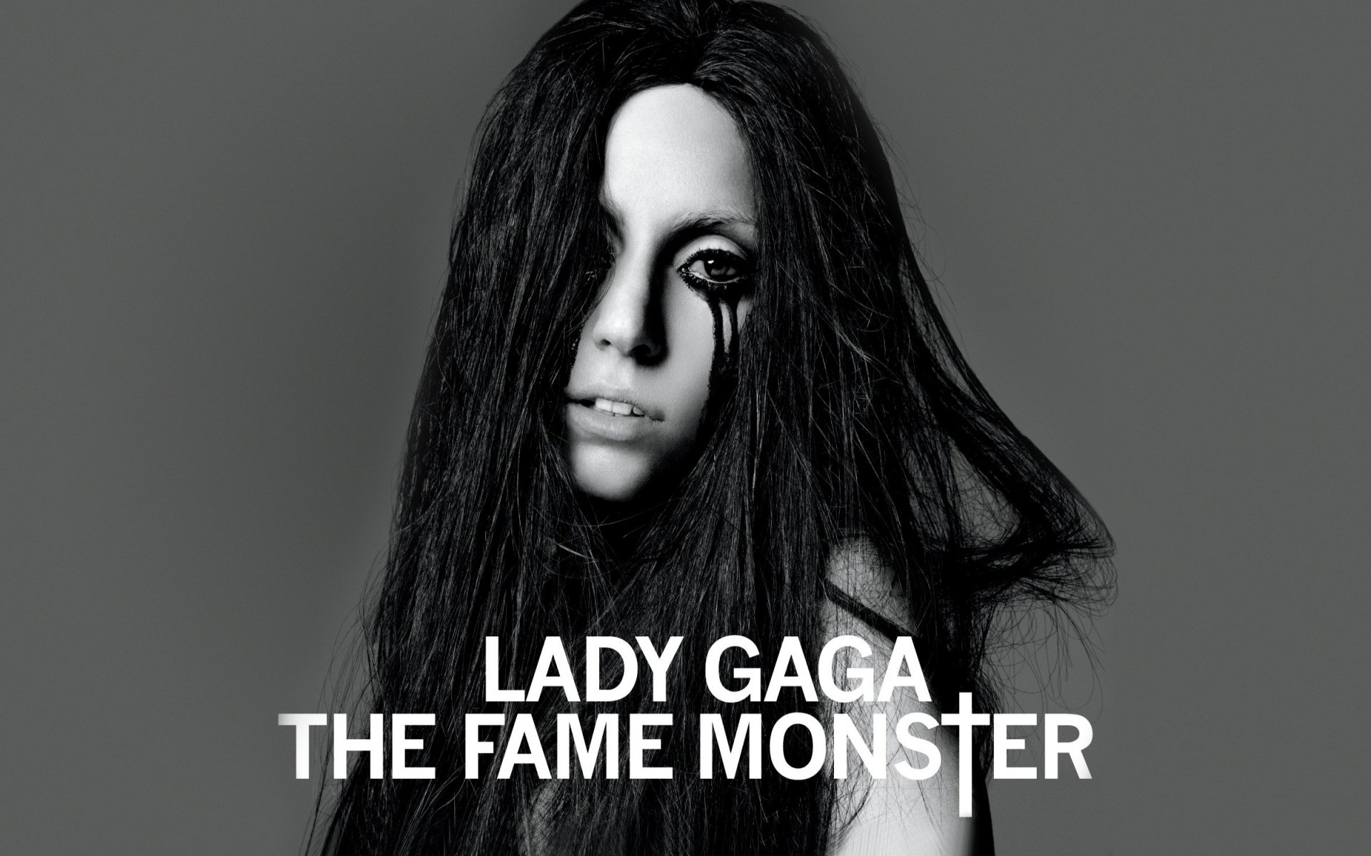 Black and white HD desktop wallpaper of Lady Gaga with long hair and dark makeup, featuring the text Lady Gaga The Fame Monster.
