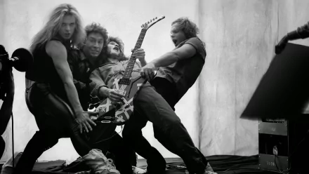 Black-and-white HD desktop wallpaper of a hard rock/heavy metal group in a wild pose, four musicians grappling a striped electric guitar, raw high-energy stage vibe.