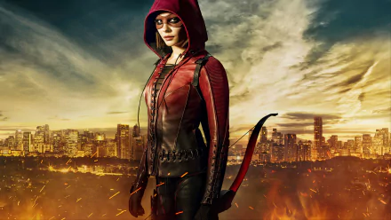 HD desktop wallpaper featuring Willa Holland as Thea Queen (Speedy) from the TV show Arrow, standing against a cityscape backdrop with dramatic sky and fiery elements.