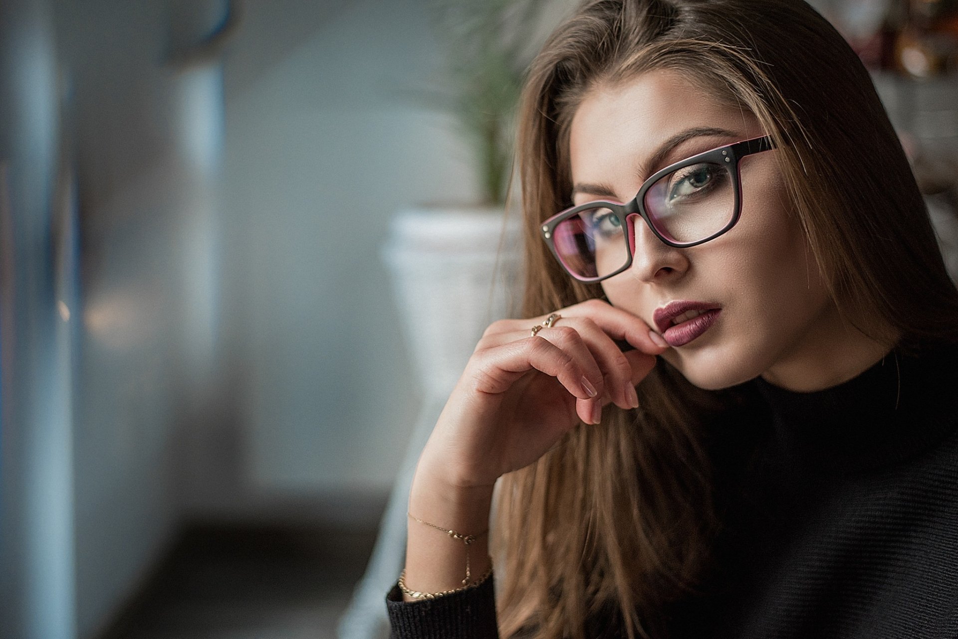 HD desktop wallpaper featuring a brunette woman wearing glasses and lipstick, gazing thoughtfully beside a blurred background.