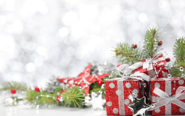 A festive 4K Ultra HD desktop wallpaper featuring glittering red gift boxes, silver ribbons, star ornaments, and green pine branches with holiday decorations.