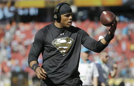 HD wallpaper featuring a person wearing a Superman logo shirt holding a football on a field, designed as a desktop background.