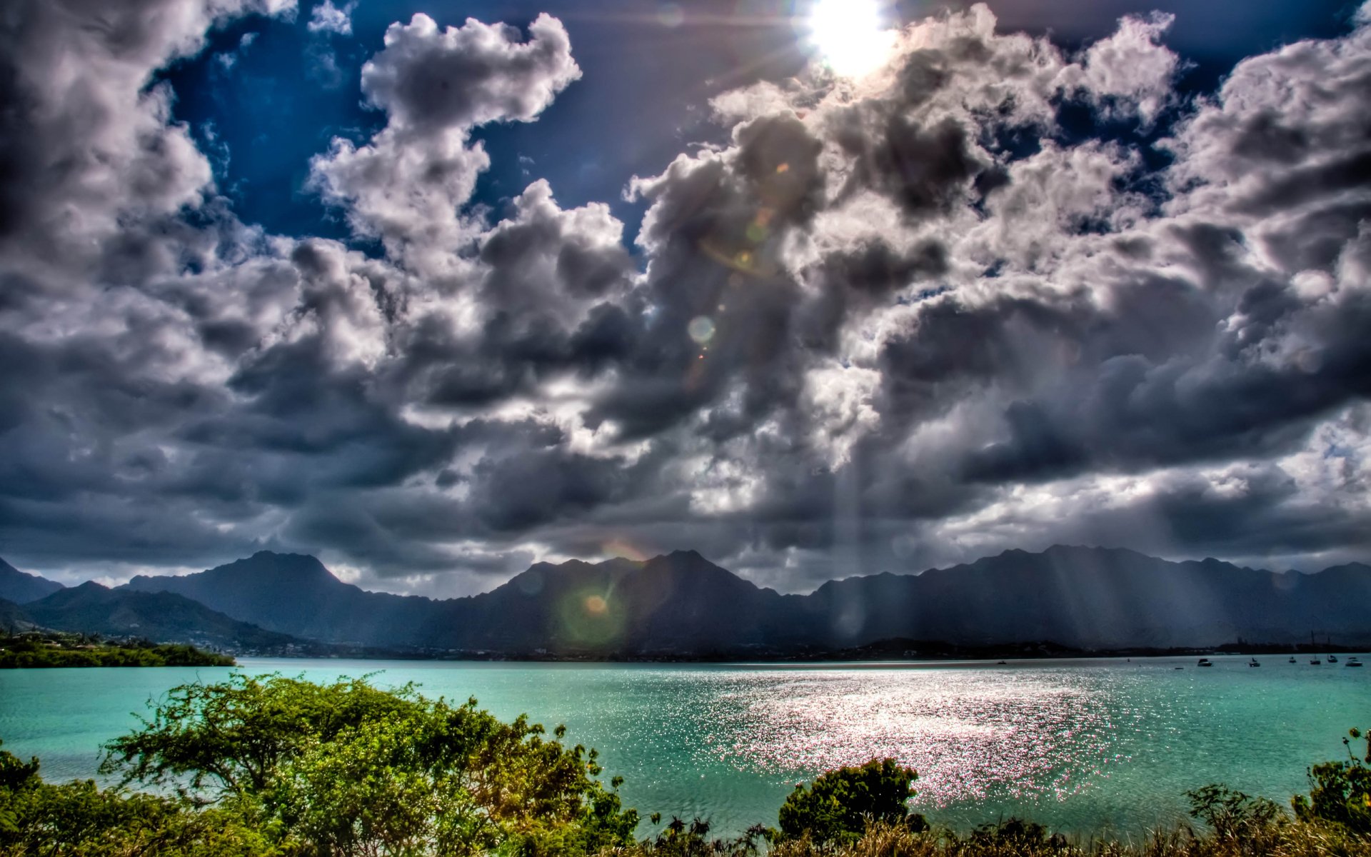 Sunbeam breaks through clouds over Oahu, Hawaii, illuminating the ocean, mountains, and lush trees in this vibrant HD desktop wallpaper.
