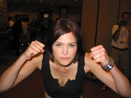 A confident woman, Morgan Webb, poses with clenched fists, showcasing determination. This HD PC desktop wallpaper captures her strong presence and charisma.