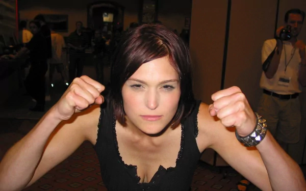 A confident woman, Morgan Webb, poses with clenched fists, showcasing determination. This HD PC desktop wallpaper captures her strong presence and charisma.
