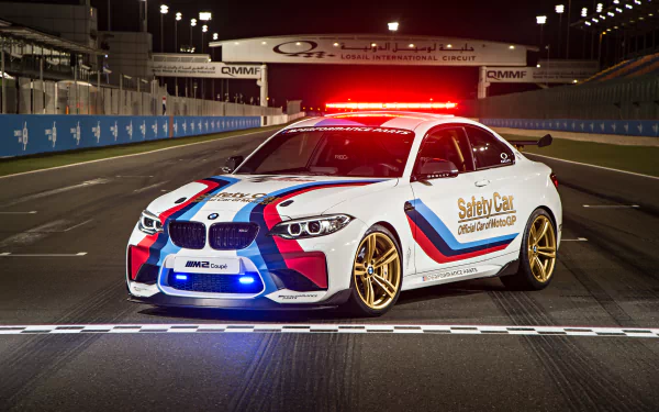4K Ultra HD PC desktop wallpaper of a BMW M2 Coupe race car vehicle — white safety car with M‑stripes and flashing red lights on a night racetrack.