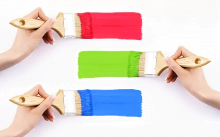 A vibrant HD desktop wallpaper featuring hands holding paintbrushes with bold strokes of red, green, and blue colors, creating a lively and colorful backdrop.