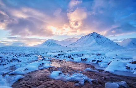 4K Ultra HD PC desktop wallpaper: Snowy mountain winter nature scene with a frozen river winding through snow-covered plains beneath a pastel sunrise sky.