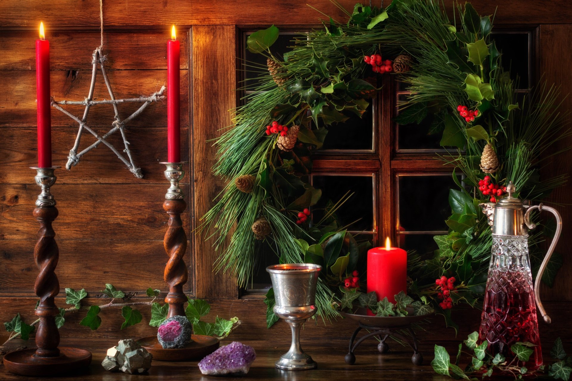 4K Ultra HD Christmas holiday wallpaper featuring a festive wreath with red berries, lit red candles, a silver cup, and a decorative star against a wooden background.