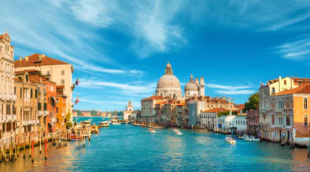 A stunning HD wallpaper of Venice, Italy, showcasing the Grand Canal adorned with historic architecture and domed buildings under a bright blue sky.