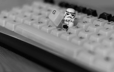 Black and white HD desktop wallpaper featuring a LEGO Star Wars stormtrooper holding a G key on a keyboard.