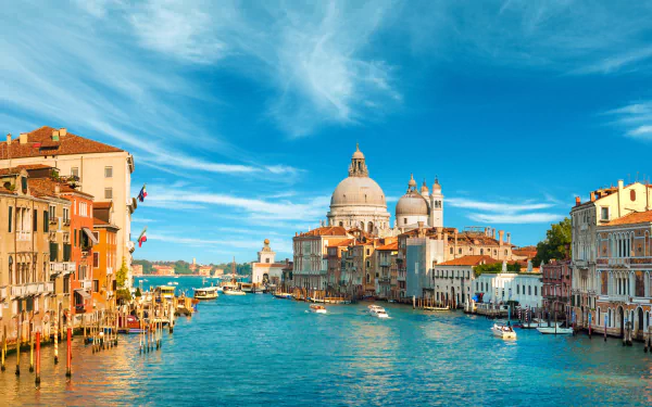 A stunning HD wallpaper of Venice, Italy, showcasing the Grand Canal adorned with historic architecture and domed buildings under a bright blue sky.