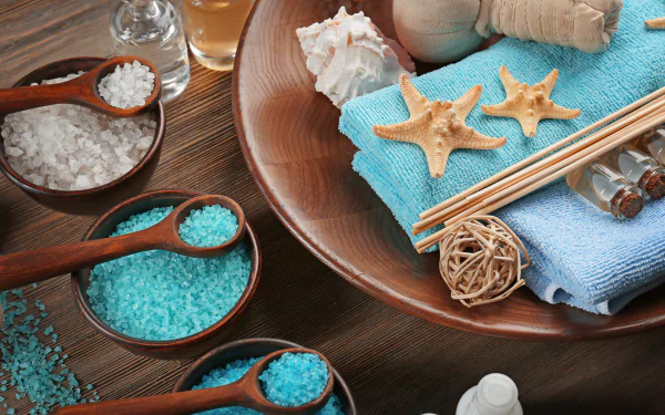 A 4K Ultra HD still life of spa essentials featuring man-made and natural elements like towels, shells, bath salts, and massage tools arranged on a wooden surface.