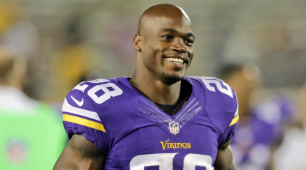 HD desktop wallpaper featuring a smiling football player in a purple Vikings jersey, number 28, on the field.