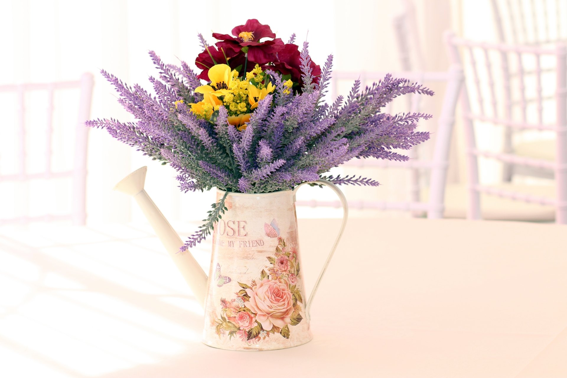 A colorful still life of a floral watering can filled with vibrant purple and yellow flowers, captured in crisp 4K Ultra HD as a PC desktop wallpaper.