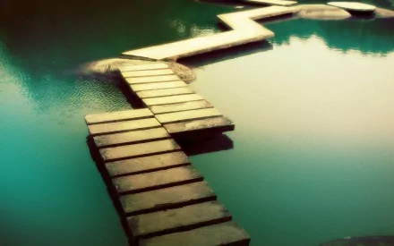 A zigzagging man-made stone path crosses over calm greenish-blue water, creating a serene and balanced HD desktop wallpaper and background.