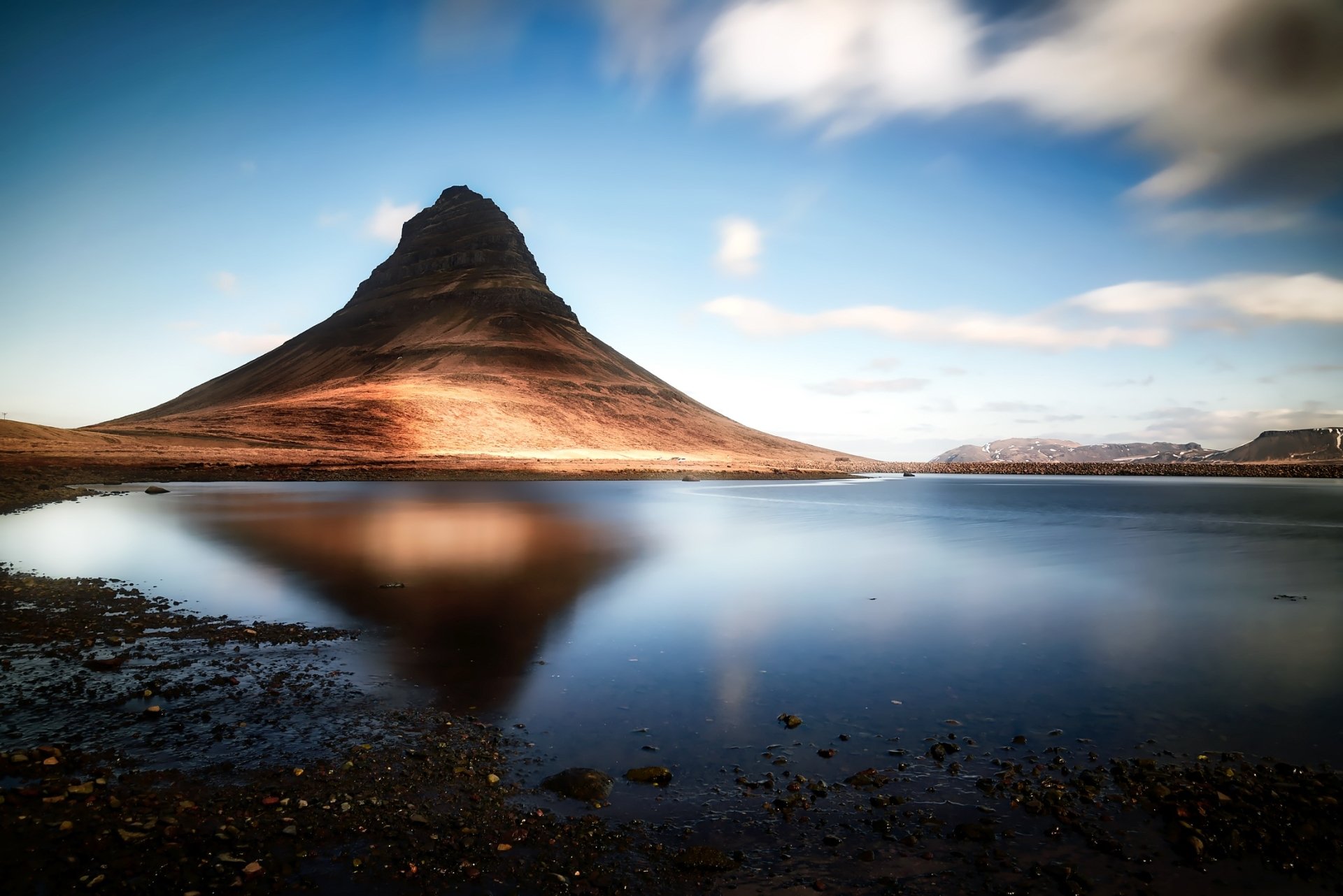 Kirkjufell peak in Iceland mirrored in a tranquil lake beneath a dramatic sky — HD PC desktop wallpaper/background celebrating rugged nature.