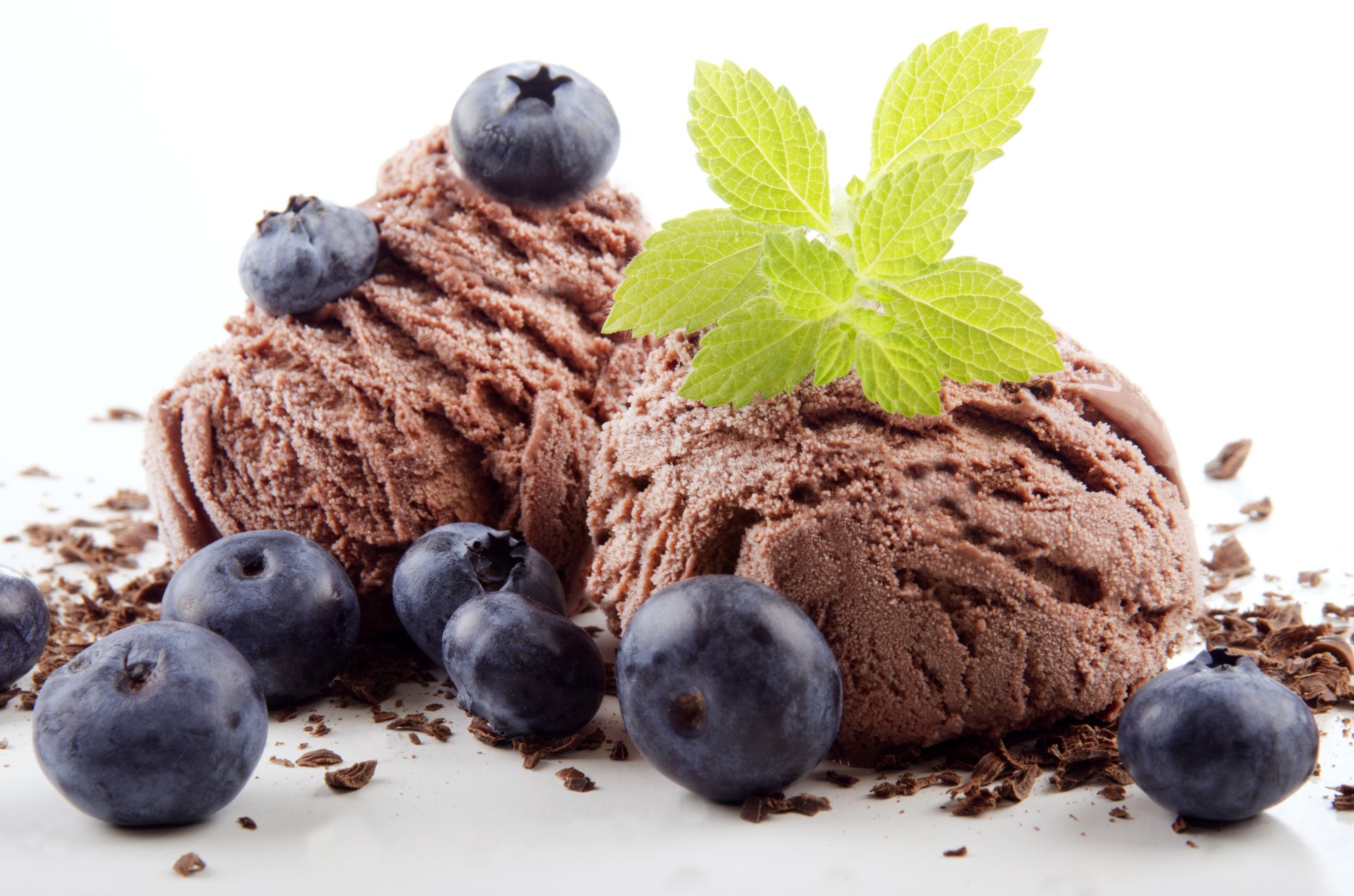 Close-up of rich chocolate ice cream scoops garnished with fresh blueberries and a green mint leaf, captured in stunning 4K Ultra HD for a vibrant PC desktop background.
