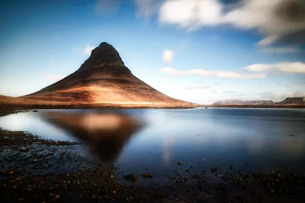 Kirkjufell peak in Iceland mirrored in a tranquil lake beneath a dramatic sky — HD PC desktop wallpaper/background celebrating rugged nature.