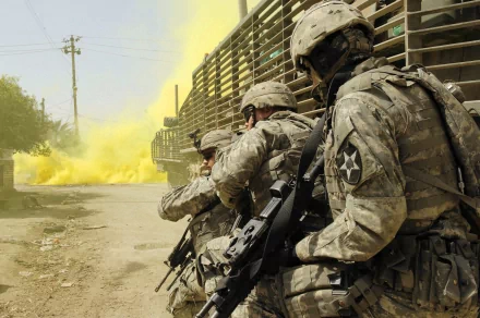 A military soldier crouches beside a smoke grenade, with a cloud of yellow smoke billowing in the background, capturing an intense moment in a tactical environment.