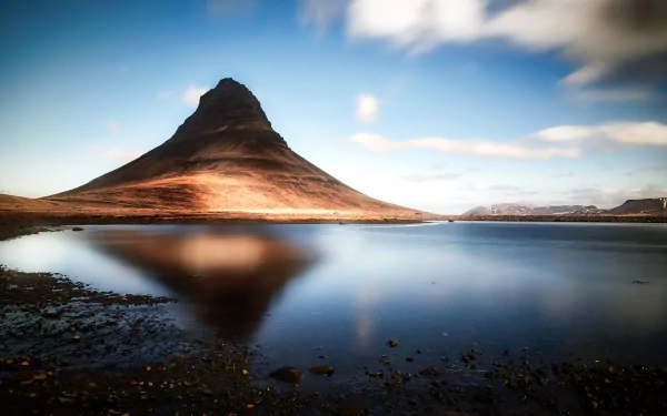 Kirkjufell peak in Iceland mirrored in a tranquil lake beneath a dramatic sky — HD PC desktop wallpaper/background celebrating rugged nature.