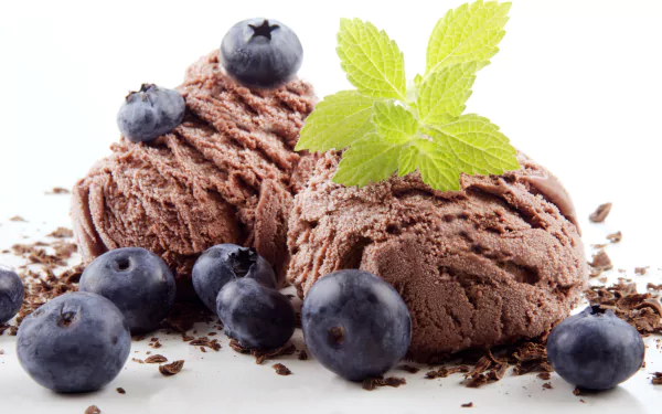 Close-up of rich chocolate ice cream scoops garnished with fresh blueberries and a green mint leaf, captured in stunning 4K Ultra HD for a vibrant PC desktop background.