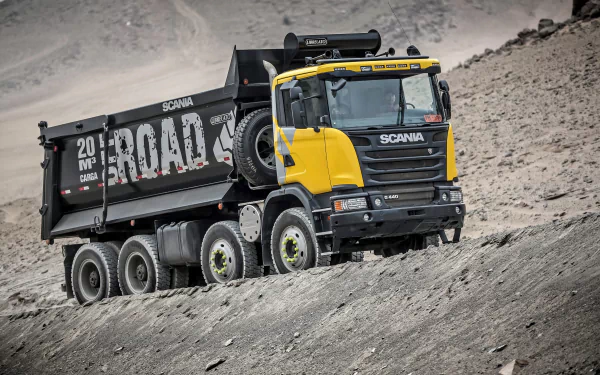 HD desktop wallpaper featuring a rugged yellow and black Scania dump truck navigating a rocky terrain.