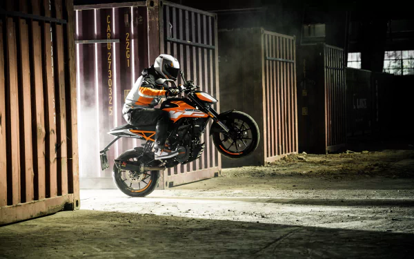 A KTM motorcycle performing a wheelie inside an industrial warehouse, captured in sharp detail as a 4K Ultra HD PC desktop wallpaper.