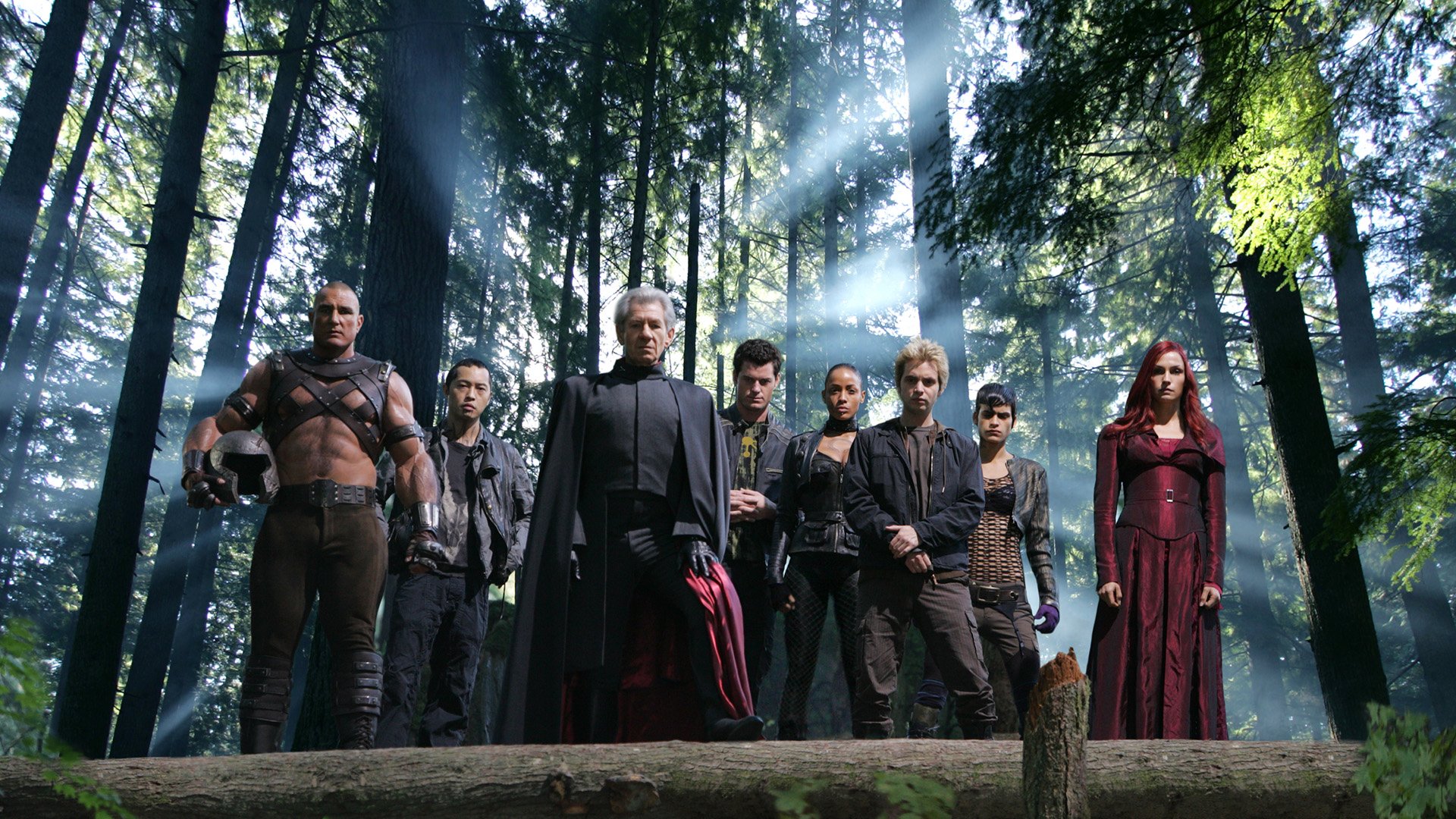 X-Men: The Last Stand HD desktop wallpaper — a group of mutants stand in a sunlit forest clearing, arranged in a dramatic lineup with rays streaming through the trees.