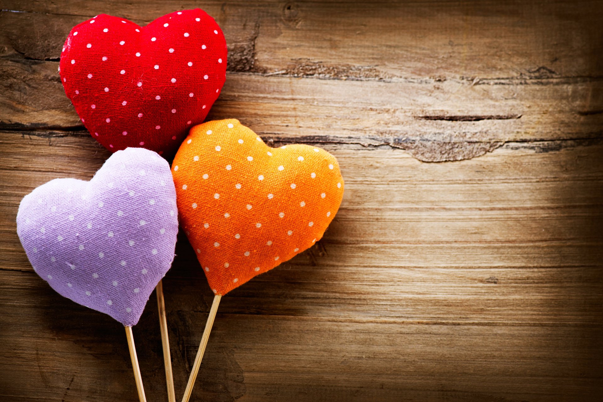 Heart-shaped red, orange, and purple polka dot cushions on sticks against a rustic wooden background, celebrating Valentine's Day in 4K Ultra HD quality.
