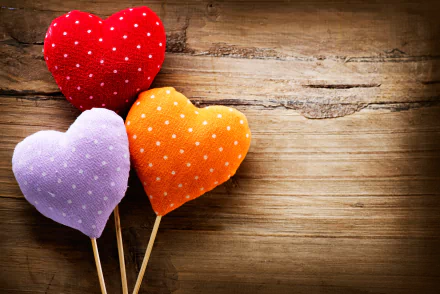 Heart-shaped red, orange, and purple polka dot cushions on sticks against a rustic wooden background, celebrating Valentine's Day in 4K Ultra HD quality.