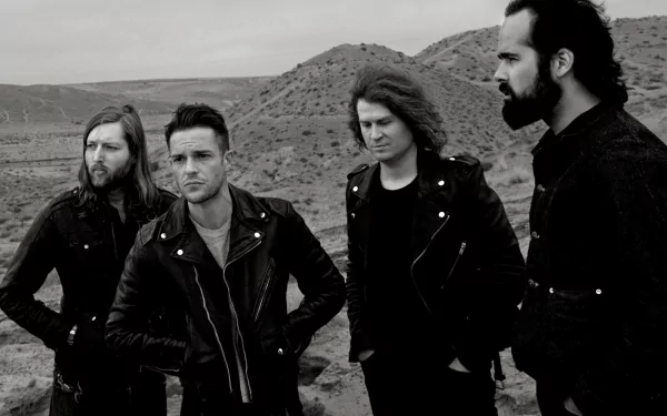 Black-and-white HD PC desktop wallpaper of a four-member rock band in leather jackets standing in a rugged desert, moody music-themed background.