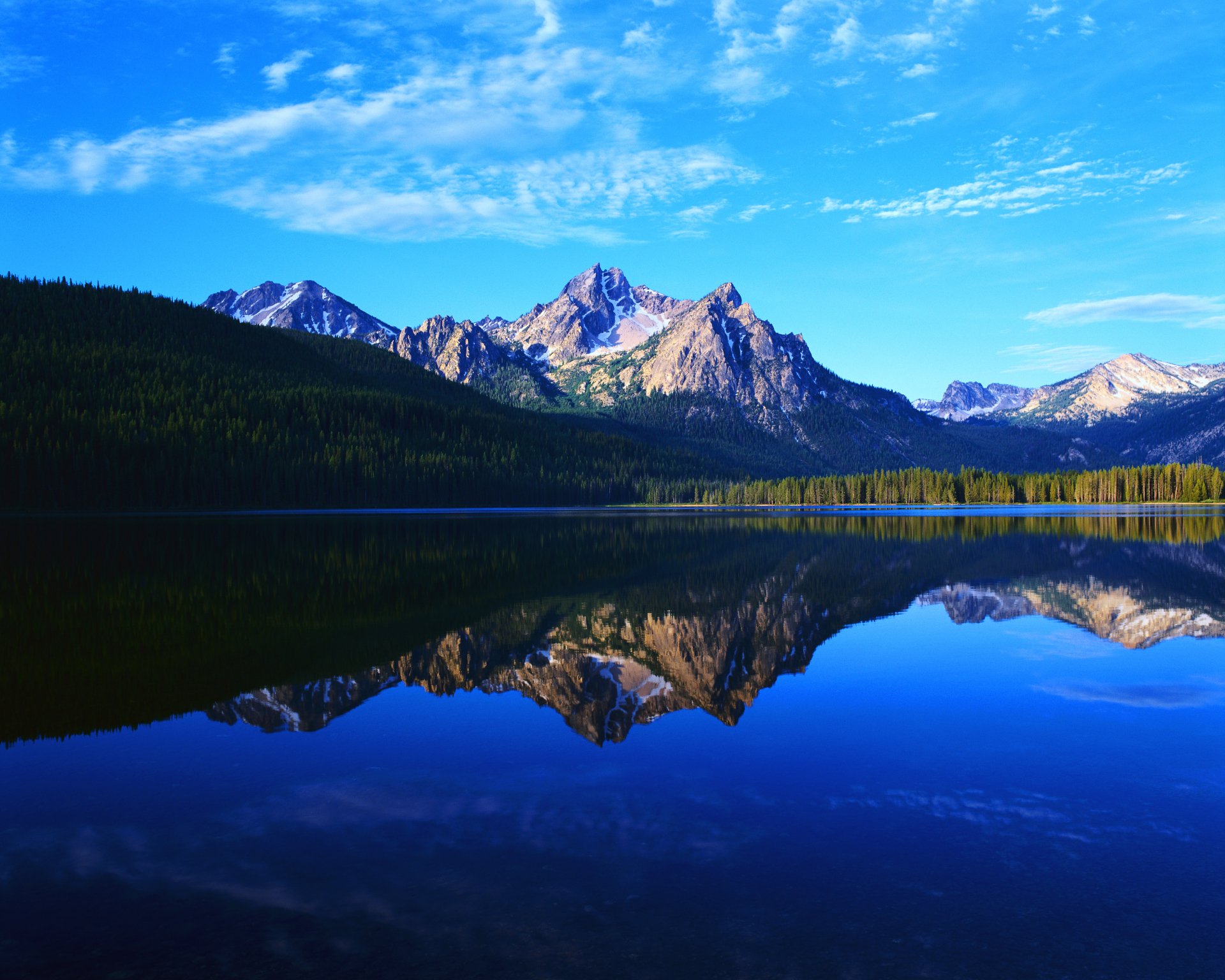 A serene nature landscape showcases majestic mountains reflected in a calm lake under a clear blue sky, making it an inspiring HD desktop wallpaper.