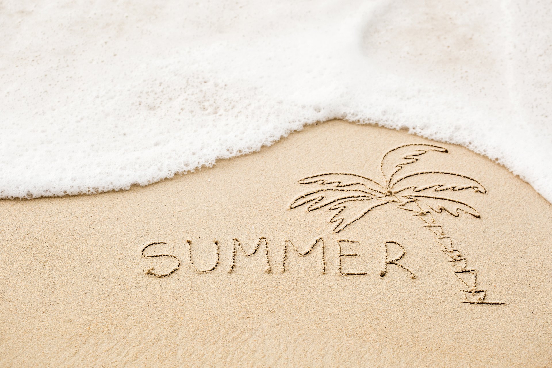 HD desktop wallpaper featuring artistic sand carving with a palm tree and SUMMER etched into the sand, with sea foam gently washing over.