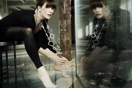 HD desktop wallpaper of brunette actress Liv Tyler, capturing her reflection against a glass surface in a moody, artistic setting.